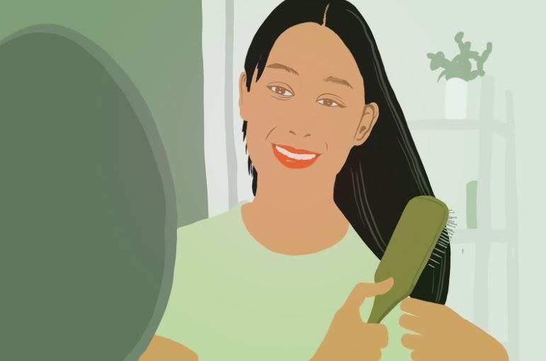 a woman smiling while combing her healthy and bouncy hair
